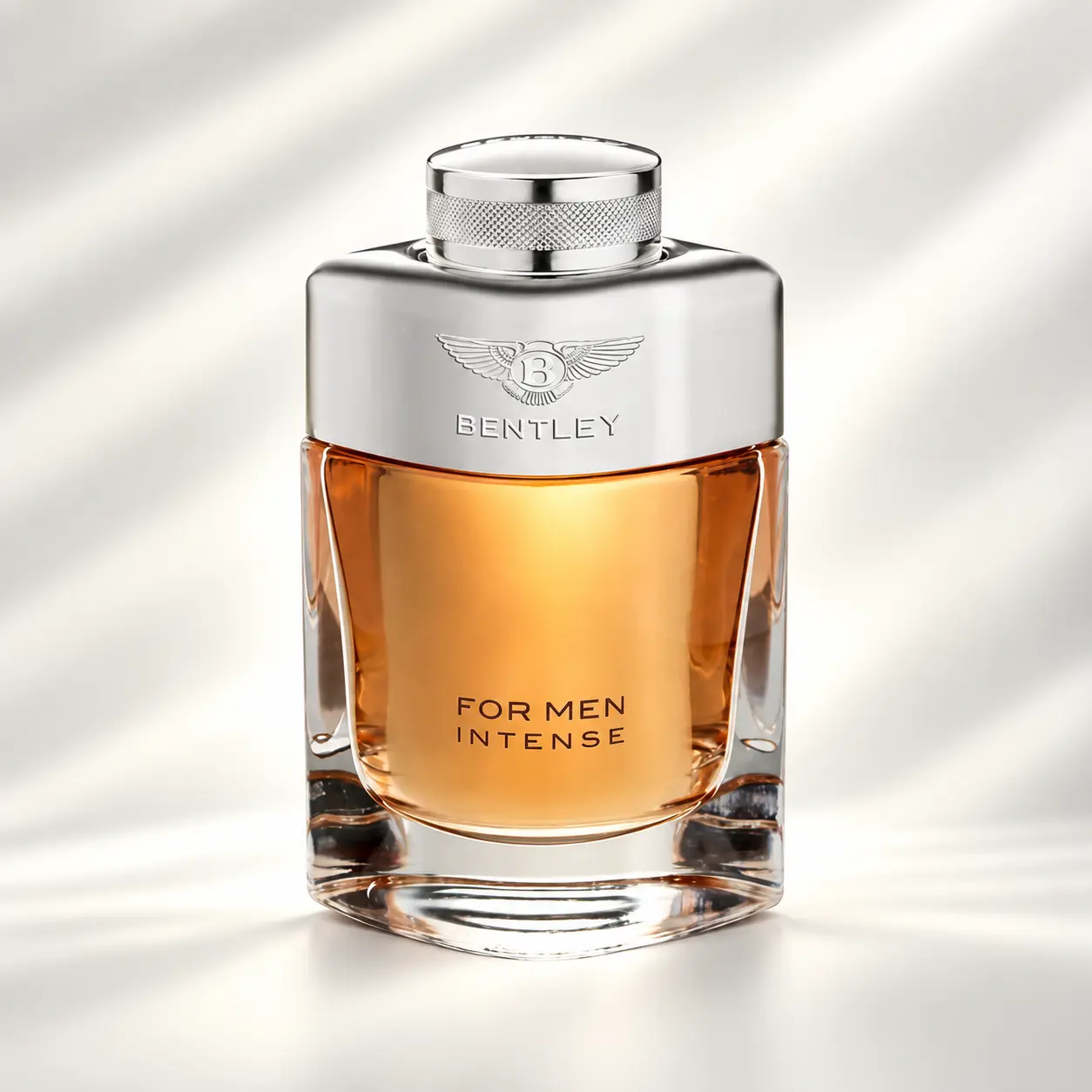 عطر بنتلی فور من اینتنس مردانه با بطری کهربایی و نقرهای بطری عطر بنتلی فور من اینتنس مردانه با مایع کهربایی، بدنه نقرهای و نشان بالدار Bentley